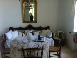 A room with a bed, a table with a lace tablecloth, and a chandelier.