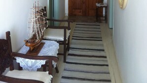 A hallway with a wooden door, a chandelier, a ship model, and a patterned rug. - Persefonis view house (Skopelos)