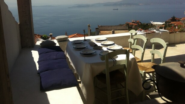 A dining area with a table set for two, overlooking a coastal view. - Persefonis view house (Skopelos)