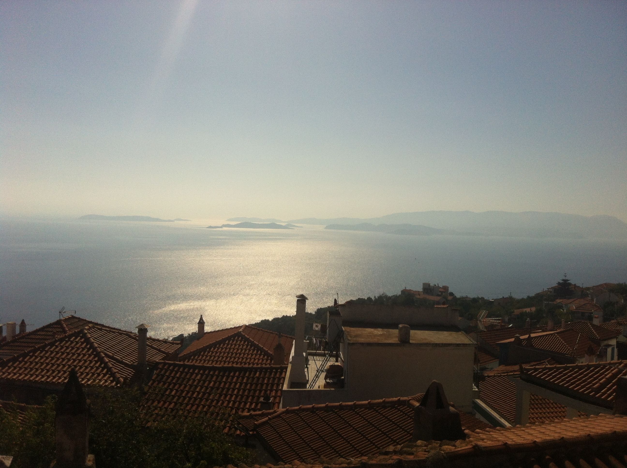 A coastal town with terracotta-roofed buildings overlooking a calm sea.