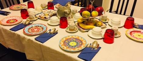 Una mesa de comedor dispuesta con platos, tazones, tazas y cubiertos.