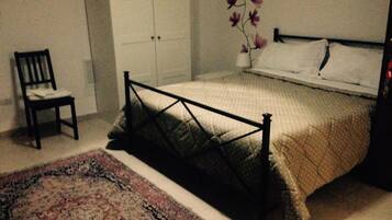 A bedroom with a bed, a chair, a wardrobe, and a floral wall decoration.
