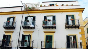 Un edificio de varios pisos con balcones, cada uno con barandilla y macetas.