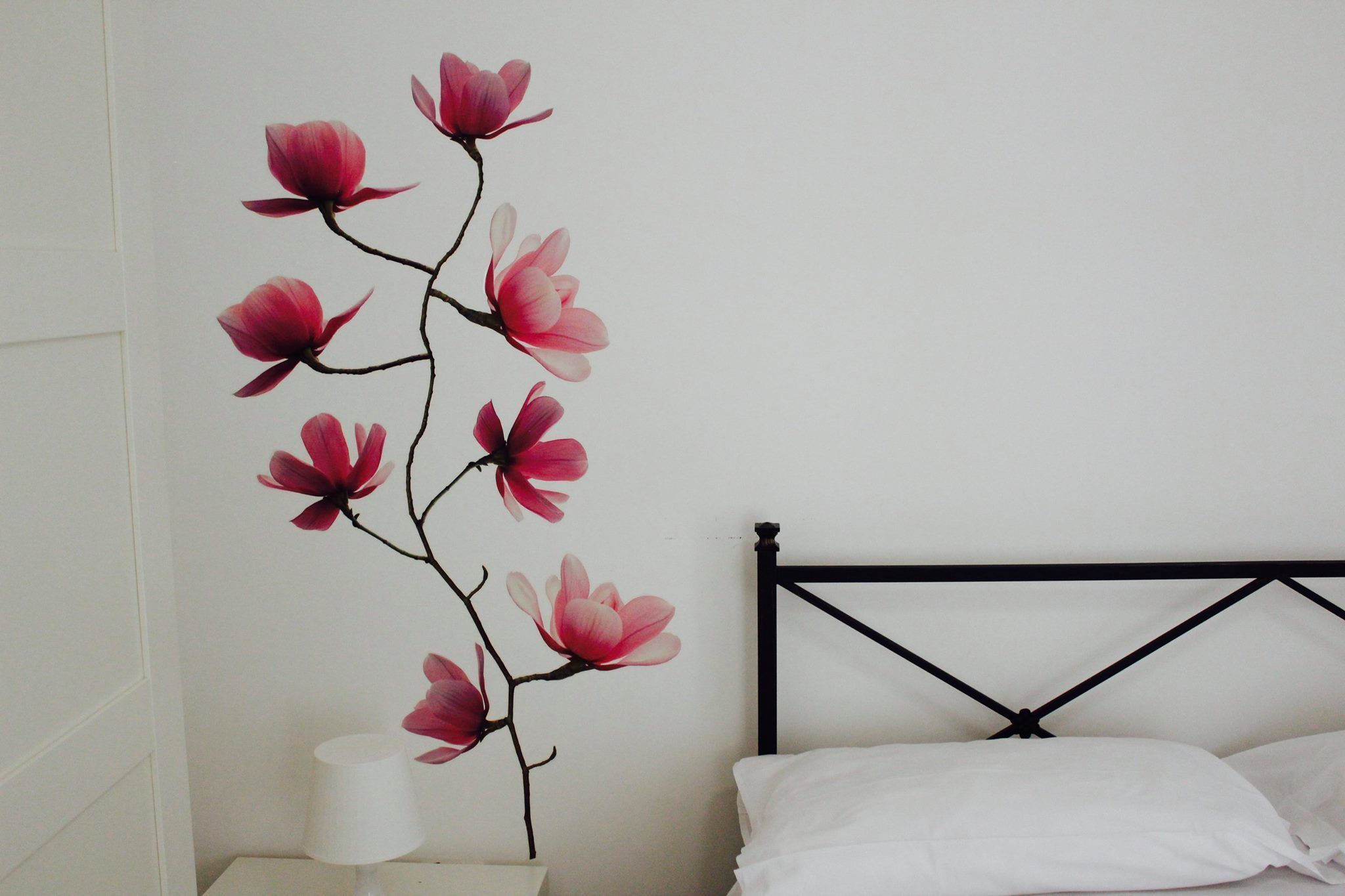 Un dormitorio con una cama, una mesita de noche y un adorno floral en la pared.