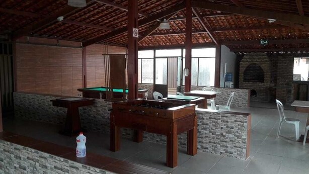 An indoor recreational area with a pool table, foosball table, and a brick fireplace. - Porto Praia Hotel (Barra dos Coqueiros)