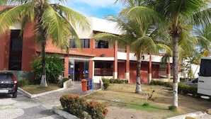 A building with a red brick facade, multiple windows, and a covered entrance. - Porto Praia Hotel (Barra dos Coqueiros)
