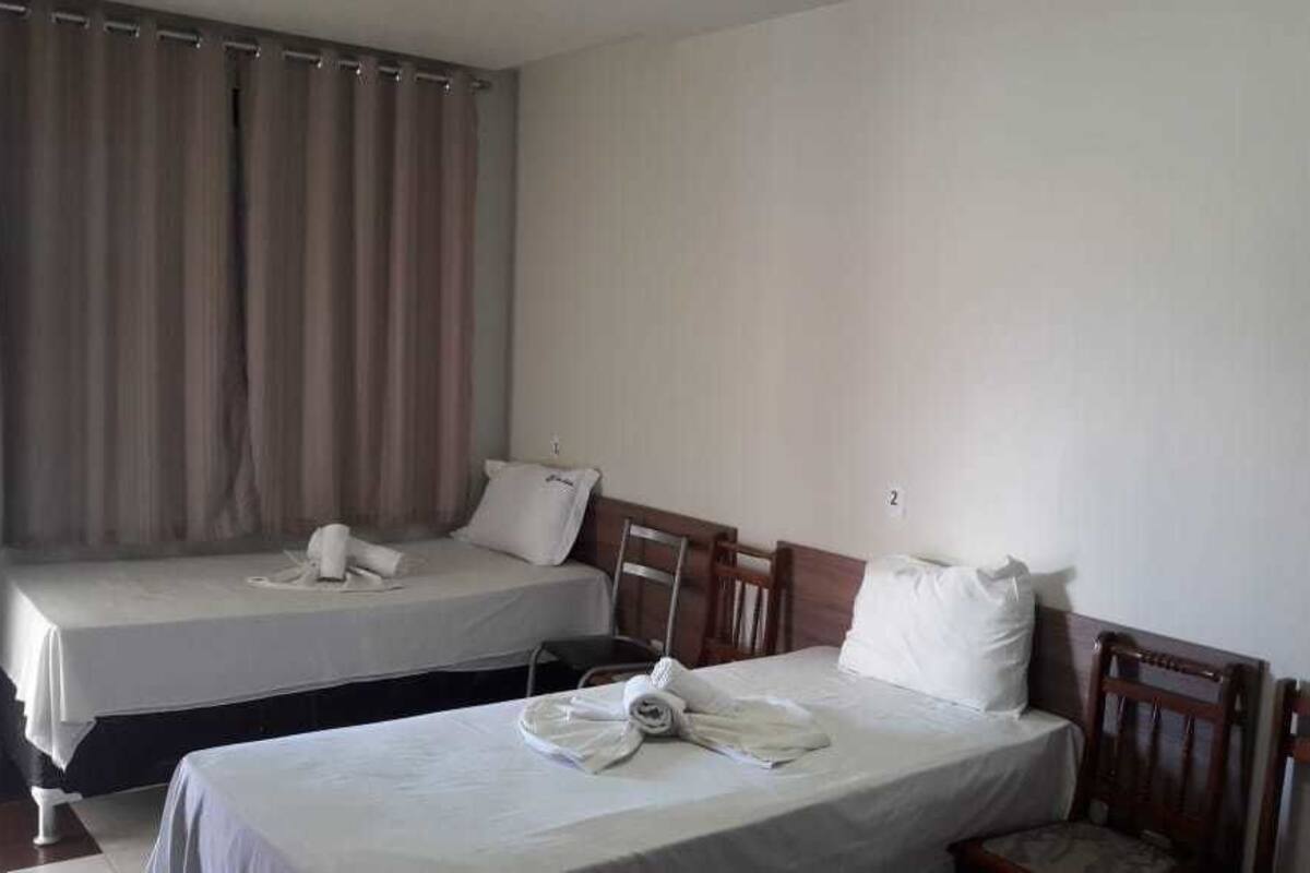 Une chambre avec deux lits simples, chacun étant équipé d’un oreiller et d’une serviette roulée.