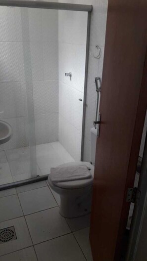 A small bathroom with a glass shower enclosure, a toilet, and a sink.