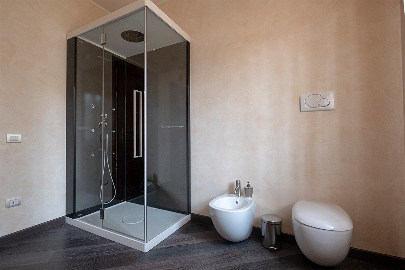Une salle de bain moderne avec une douche à parois de verre, des toilettes blanches et un bidet.