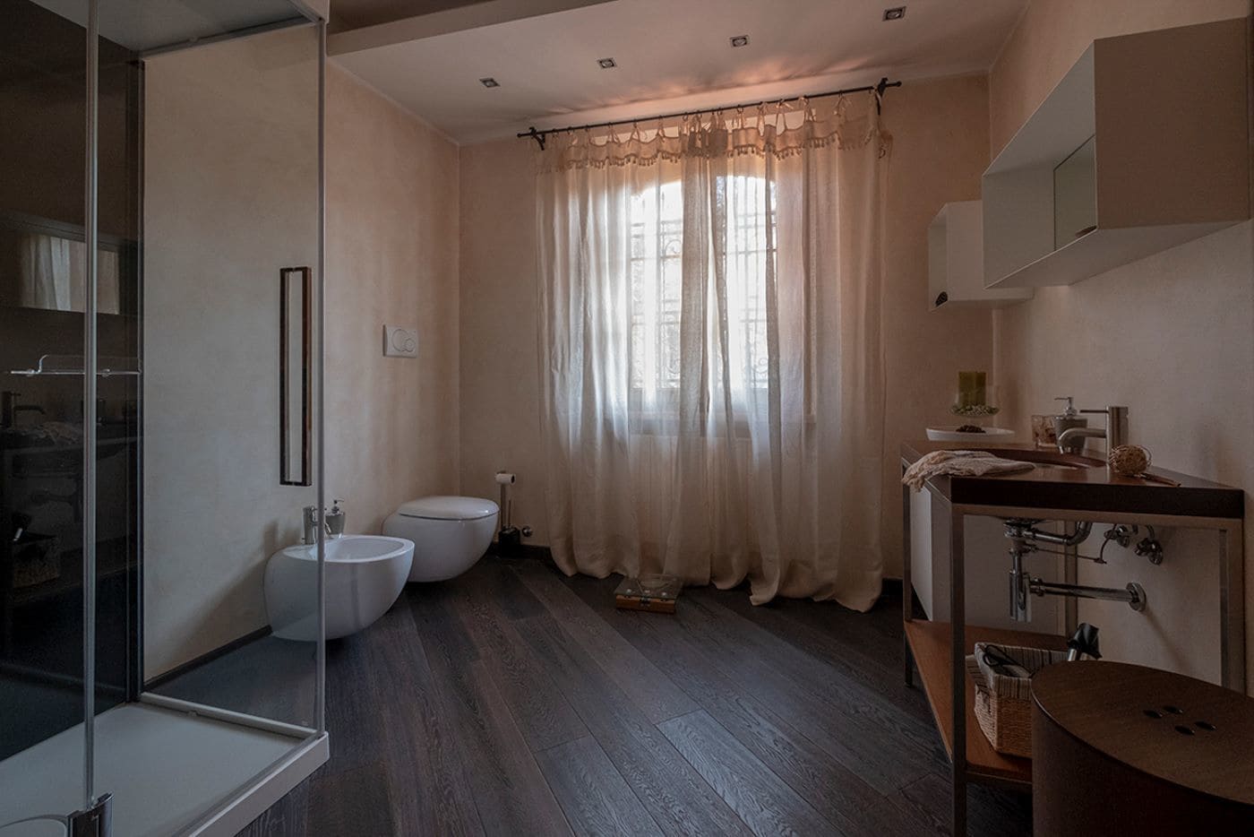 Ein modernes Badezimmer mit Duschabtrennung aus Glas, Doppeltoilette und Waschtisch mit Becken und Spiegel.