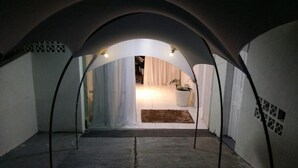 A cozy, dimly lit room with a curved ceiling, a bed, a potted plant, and a small rug. - Hotel Porto Fino (Pontal do Parana)