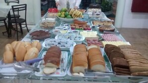 A buffet table with various food items including breads, pastries, and fruits. - Hotel Porto Fino (Pontal do Parana)
