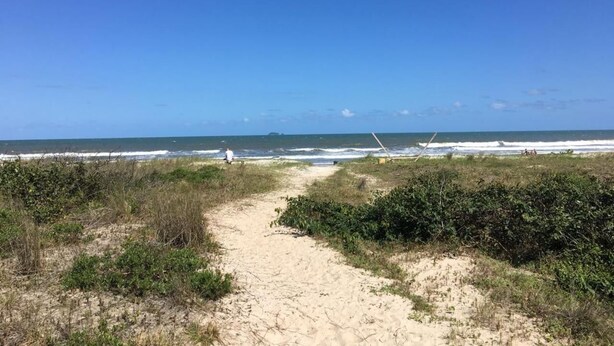 A sandy path leading to a beach with sparse vegetation and a clear blue sky. - Hotel Porto Fino (Pontal do Parana)