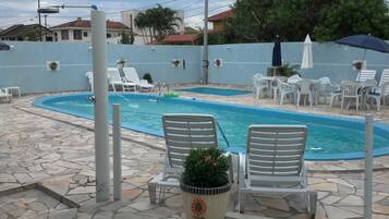 Uma área de piscina com espreguiçadeiras e guarda-sóis.