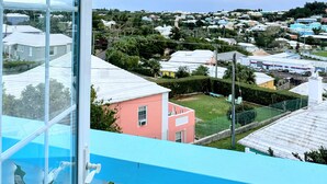 Un balcon offrant une vue dégagée sur un quartier résidentiel, avec ses maisons et sa végétation.