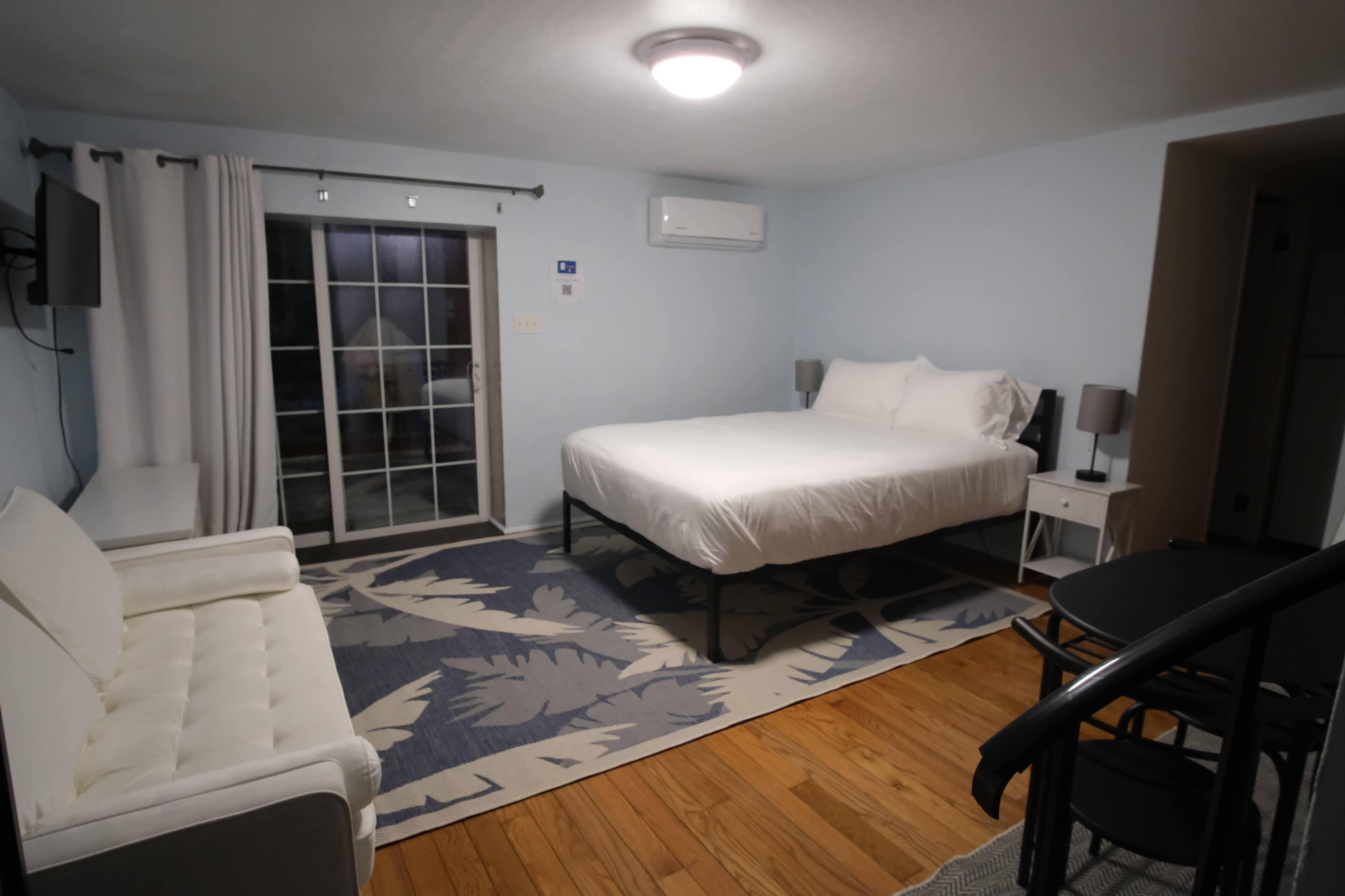 A bedroom with a bed, a chair, a desk, and a window with curtains.