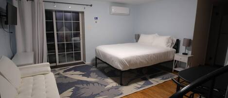 A bedroom with a bed, a chair, a desk, and a window with curtains.