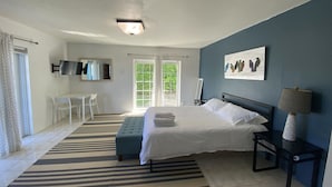 Une chambre à coucher avec un lit, un bureau, une chaise, un téléviseur et un tableau.