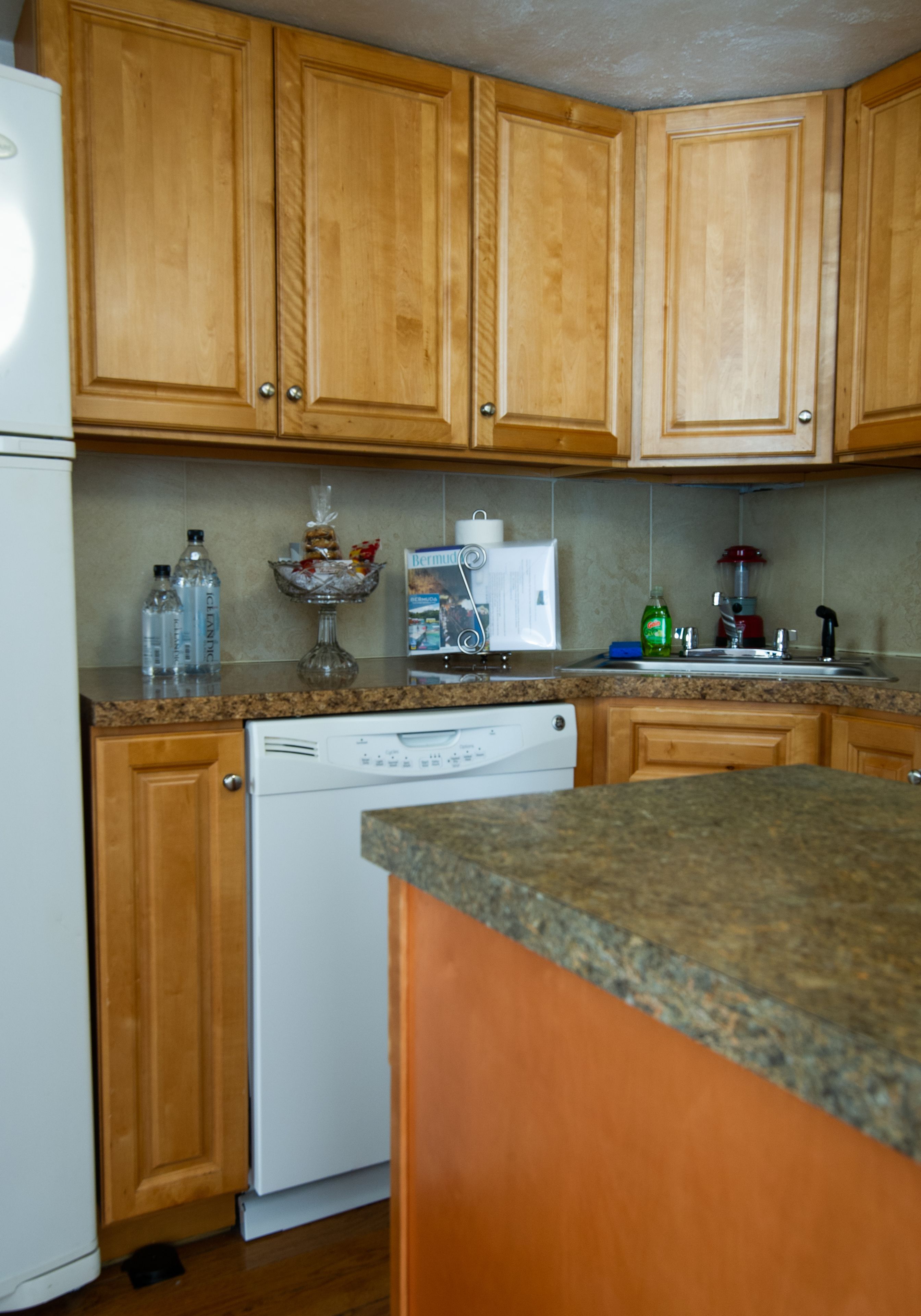 A kitchen with wooden cabinets, a dishwasher, and a granite countertop.