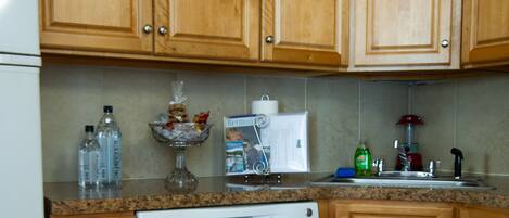 A kitchen with wooden cabinets, a dishwasher, and a granite countertop.