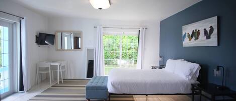 Una camera da letto con un letto, una scrivania, una sedia, una TV e una finestra con tende.
