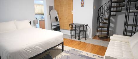 Un dormitorio con una cama, una pequeña mesa con sillas, un sofá y una escalera.