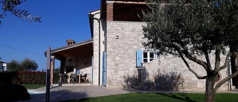 A stone building with a covered patio and a tree in front.