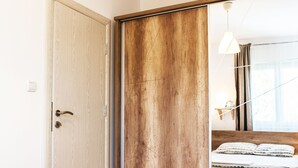Une chambre avec une armoire en bois, un lit avec une literie à motifs et une table de chevet avec une lampe.