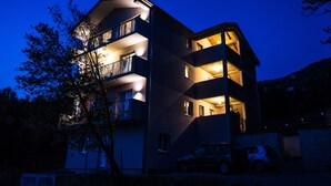 Un immeuble à plusieurs étages, doté de balcons, avec une voiture garée devant.