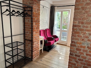 A room with a brick wall, a red chair, a black metal shelf, and a white table. - Apartment in the Geteviertel - close to the city, trade fair, university, stadium and Weser cycle path (Schwachhausen)