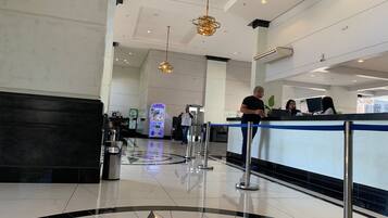 A hotel lobby with a reception desk, a vending machine, and a decorative floor pattern.