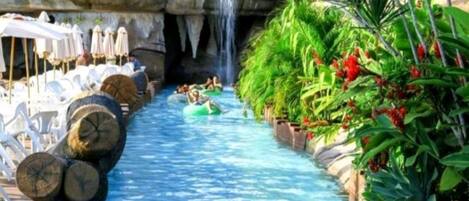 A water slide with people enjoying the ride, surrounded by lounge chairs and umbrellas.