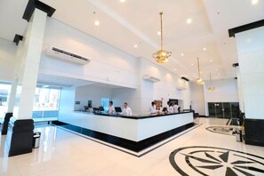 Zona de recepción de hotel con mostrador central, personal y un gran diseño decorativo en el suelo.