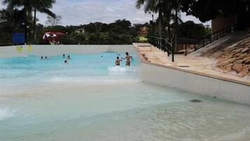Ein Schwimmbecken mit klarem Wasser, umgeben von einer gefliesten Terrasse und Palmen.