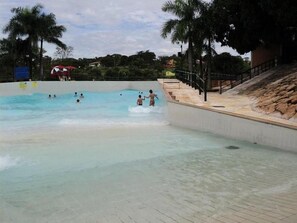 Una piscina con agua cristalina, rodeada por un solado de baldosas y palmeras.