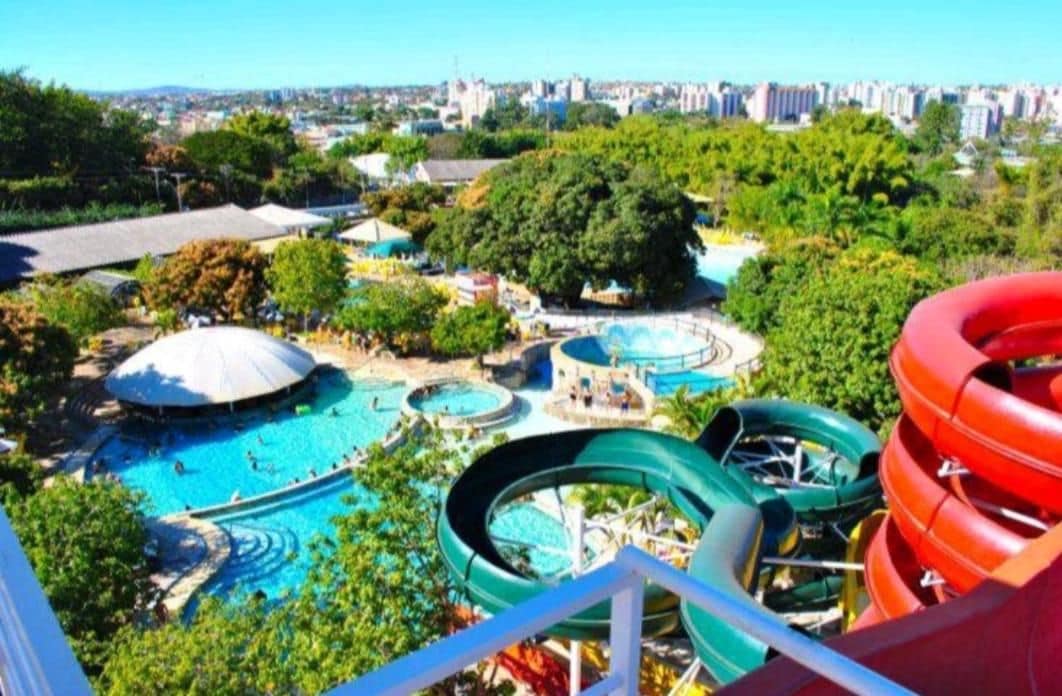 A water park with multiple slides and pools, surrounded by trees and buildings.
