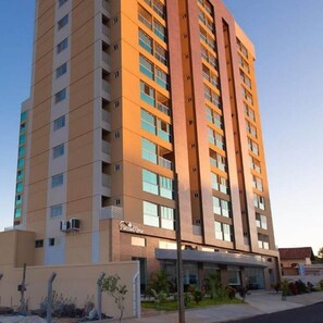 Un hotel de varios pisos con un diseño moderno, que destaca por una estructura vertical prominente y un techo plano.