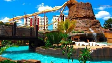 Parque acuático con una gran formación rocosa, un puente y una zona de piscina.