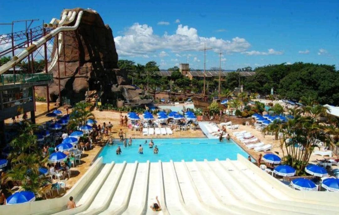 A water park with a large pool, multiple slides, and beach areas with umbrellas.