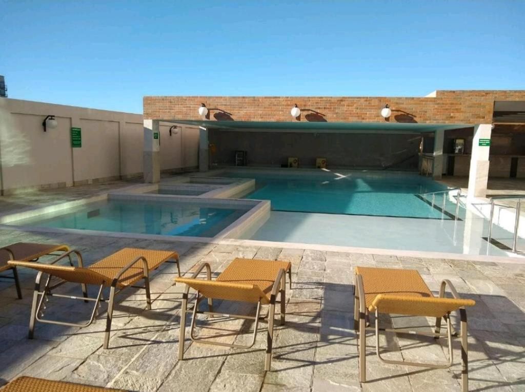 Una piscina con sillones de descanso y una pared de ladrillo.