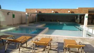 Una piscina con sillones de descanso y una pared de ladrillo.