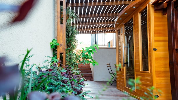 A wooden deck with a pergola, potted plants, and a staircase leading to a door.