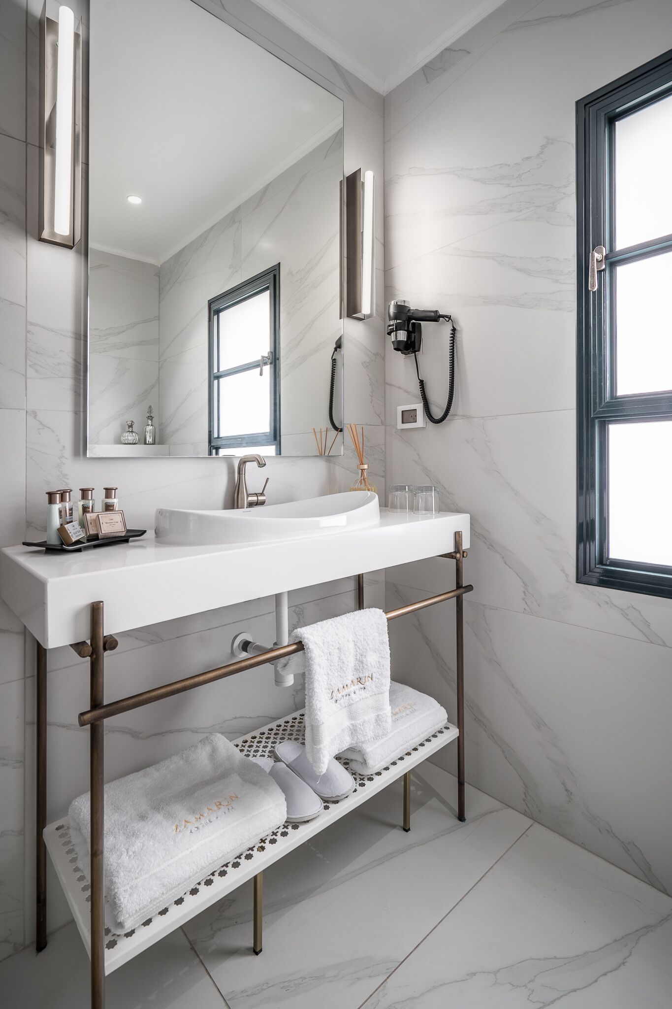 A modern bathroom with a white sink, a large mirror, and a towel rack.