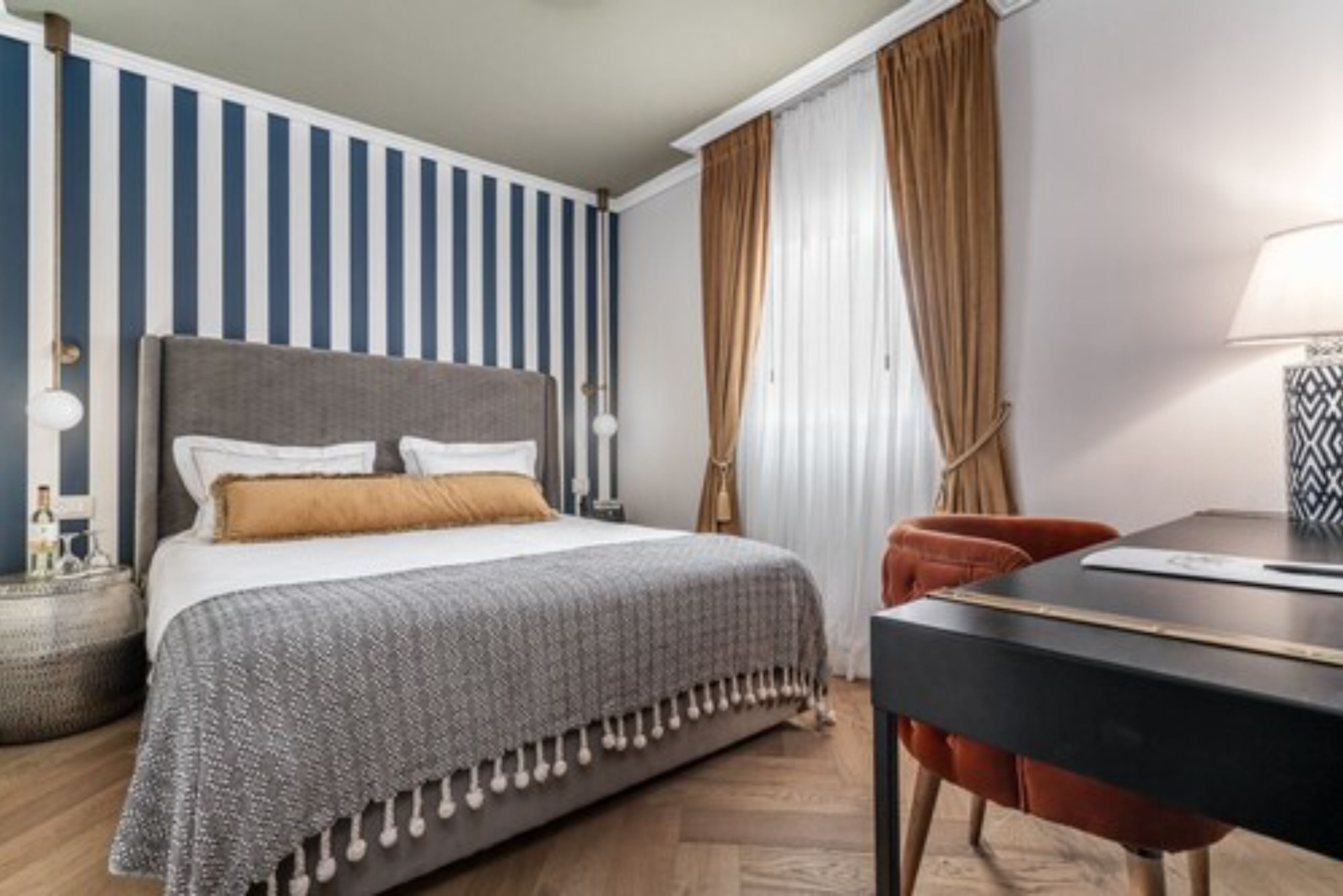 A bedroom with a bed, bedside tables, a desk, and a chair.