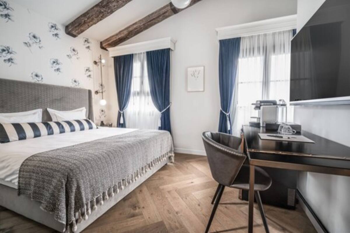A modern bedroom with a large bed, a desk, and a chair.