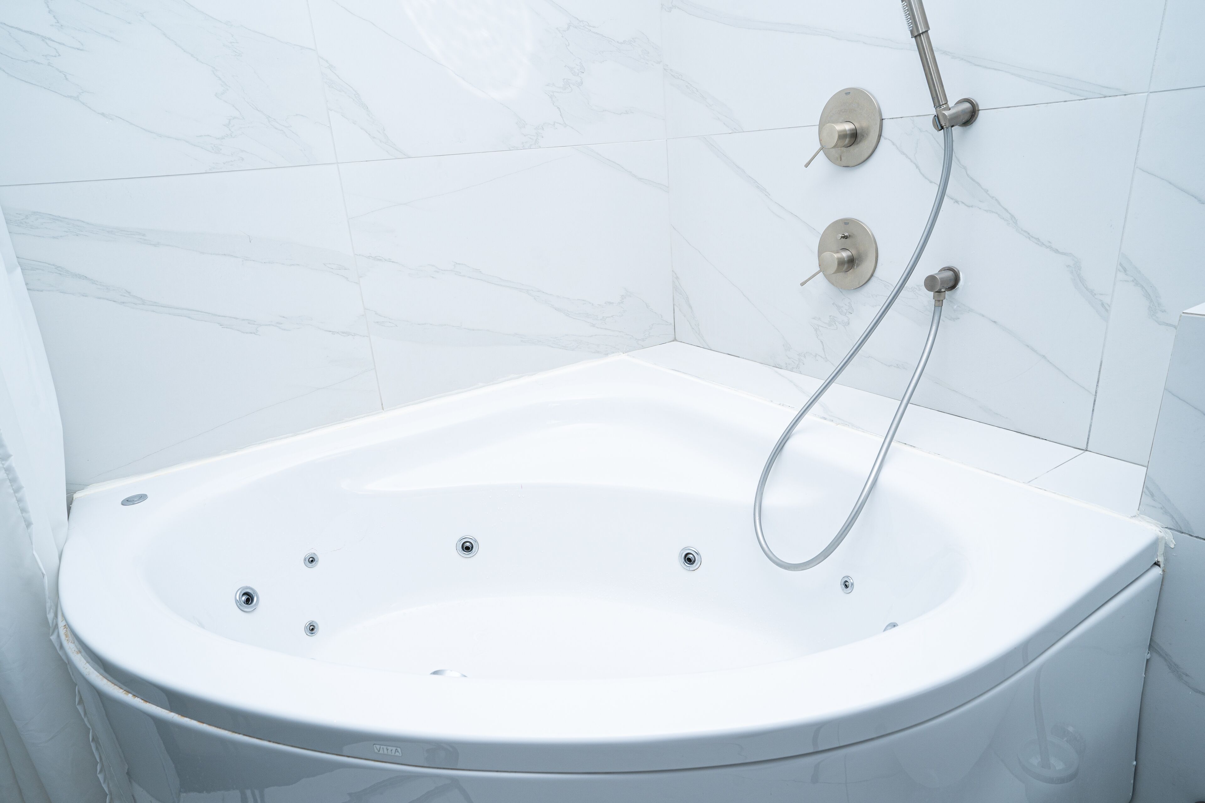 Un baño moderno con una bañera independiente, un cabezal de ducha manual y un panel de control en la pared.