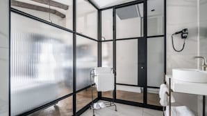 A modern bathroom with a glass partition, a white sink, and a towel rack.