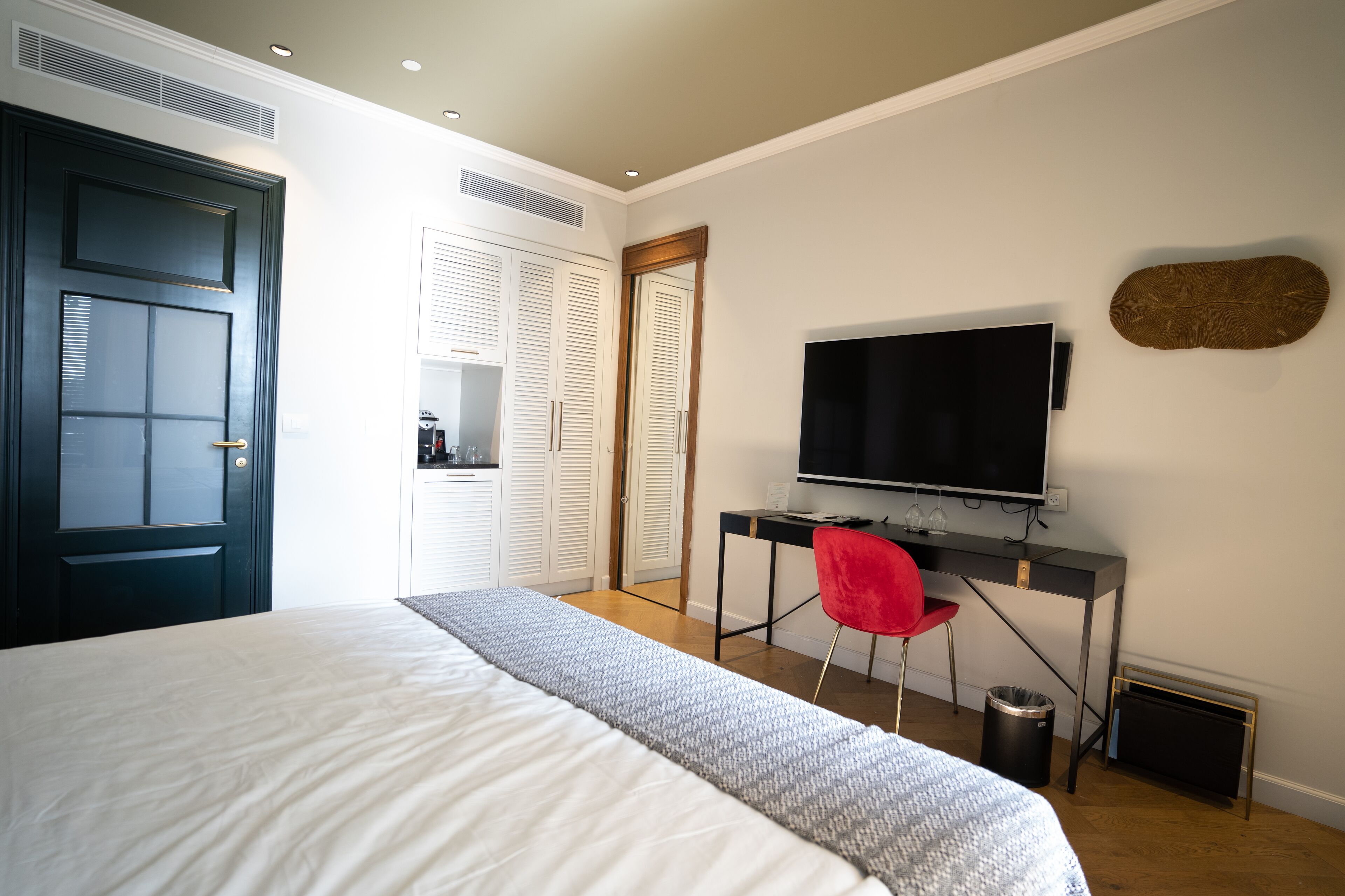 A bedroom with a bed, a desk with a chair, a television, and a wardrobe.