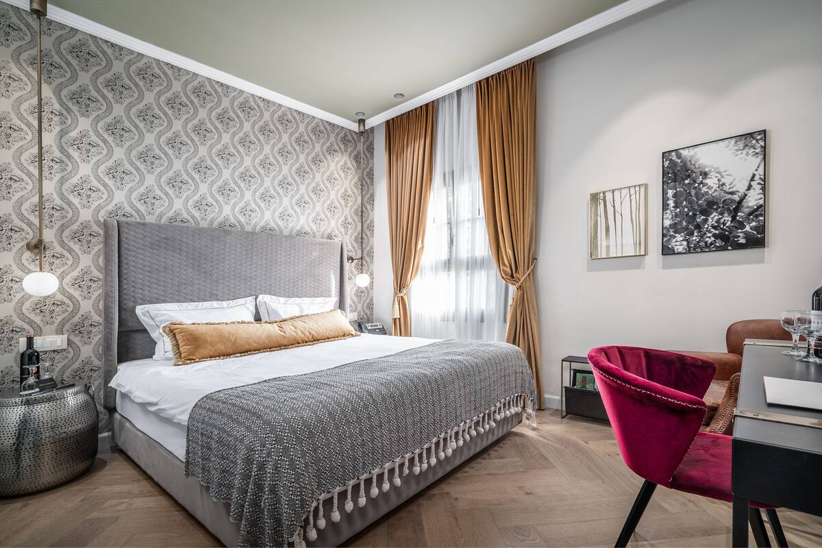A modern bedroom with a large bed, a desk, and a chair.