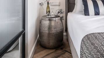 A bedroom with a bed, a round side table, a wall clock, and a floral wallpaper pattern.